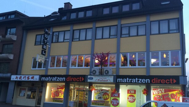 Un edificio con varias fachadas comerciales, incluyendo 'matratzen direct' y 'Palast'.