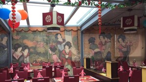 Un restaurante con sillas y mesas rojas, decorado con faroles rojos y adornos colgantes.