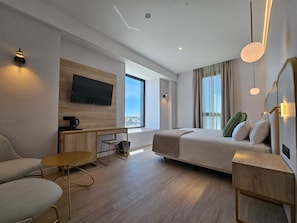 A modern hotel room with a bed, a desk, a chair, a TV, and a large window. - Malaga Vibes (Málaga)