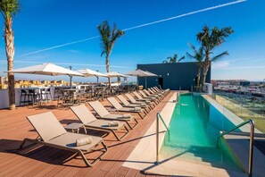 A rooftop pool area with lounge chairs and umbrellas, a pool, and a city view. - Malaga Vibes (Málaga)