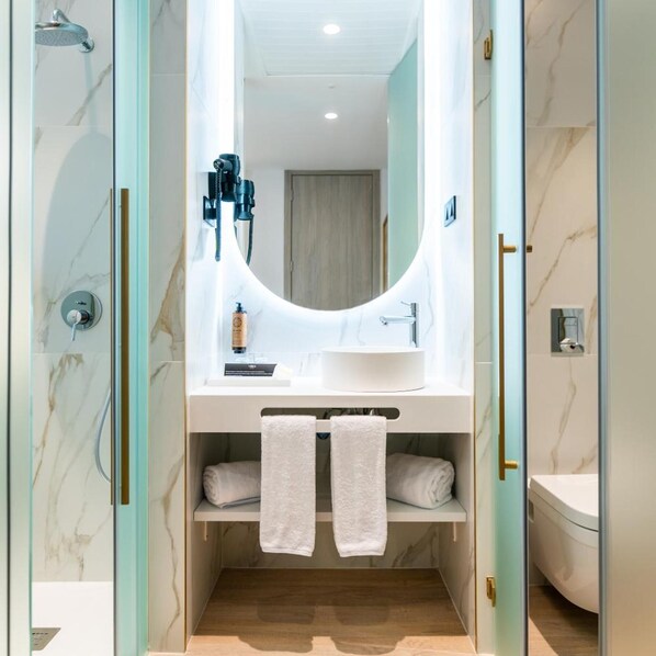 A modern bathroom with a glass-enclosed shower, a white sink with a mirror above it, and two towels hanging on a shelf. - Malaga Vibes (Málaga)