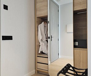 A walk-in closet with a robe hanging, a mirror, and a lamp on a shelf. - Malaga Vibes (Málaga)
