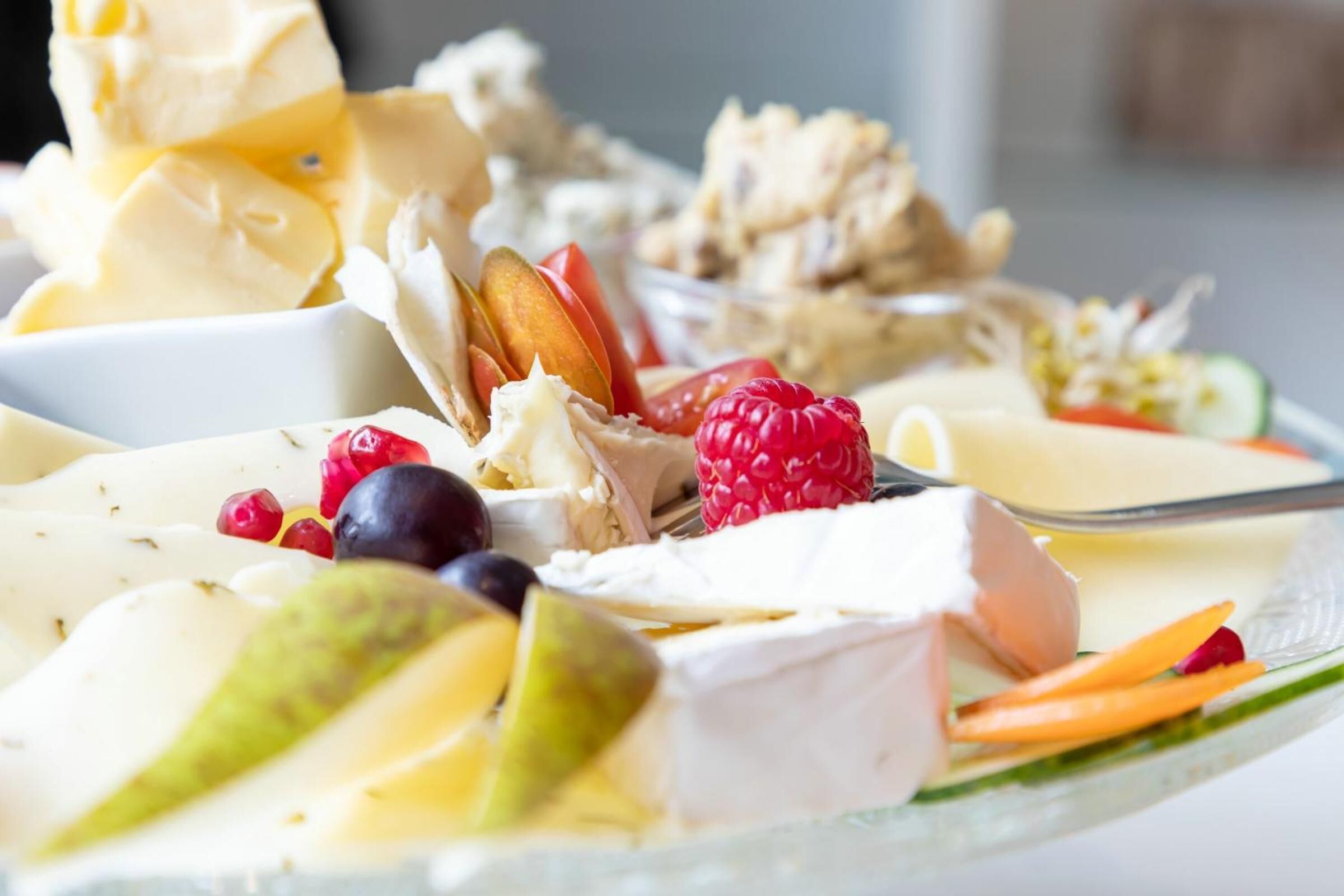 A variety of cheeses and fruits on a plate.
