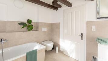 Ein modernes Badezimmer mit Badewanne, Toilette und Waschbecken.