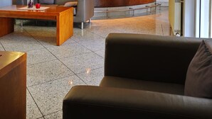 A modern lobby with a curved reception desk, seating area, and a bar. - Hotel B99 (Offenbach am Main)