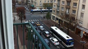 A multi-story residential building with balconies, a pedestrian street, and parked cars. - Hotel Bernieres (Caen)