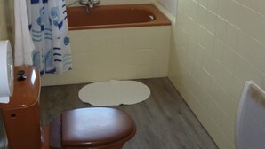 A bathroom with a bathtub, toilet, and a window. - Hotel de L'avenue (Bonson)