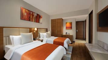 A hotel room with two beds, a flat-screen TV, a painting, and a wooden wardrobe.
