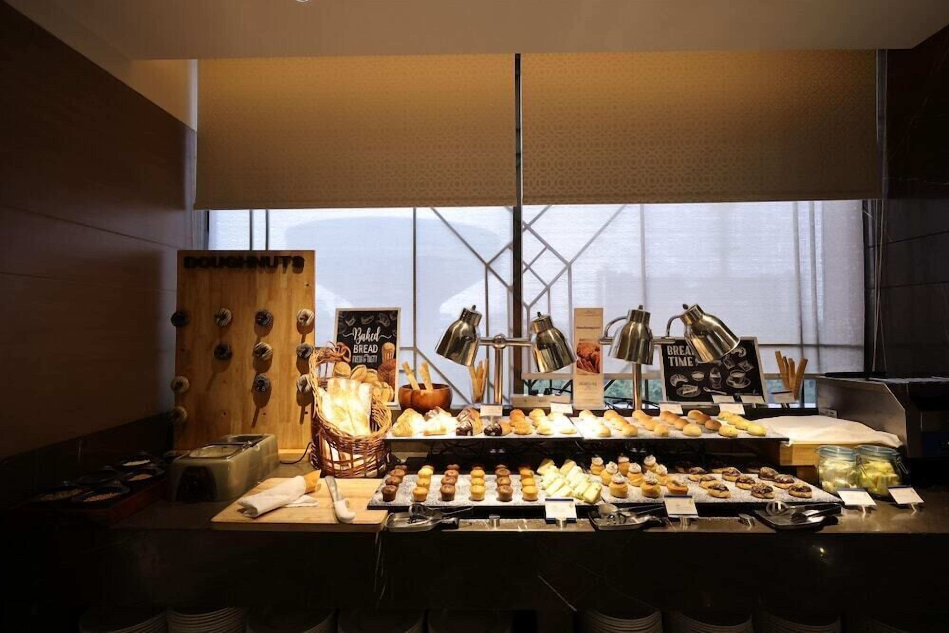 A bakery counter with various baked goods and a sign that reads 'Baked Bread Freshly Baked.'