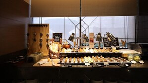 Een bakkerij toonbank met diverse gebakken producten en een bord waarop staat 'Vers gebakken brood'.