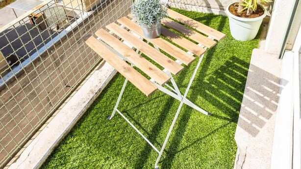 A balcony with artificial grass, a wooden bench, a potted plant, and a view of the cityscape. - Apparthotel T3 Epicservices Saint-charles (Marseille)