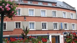 A multi-story building with a brick facade, multiple windows, and a sign indicating a hotel. - Hotel De Normandie (Gournay-en-Bray)