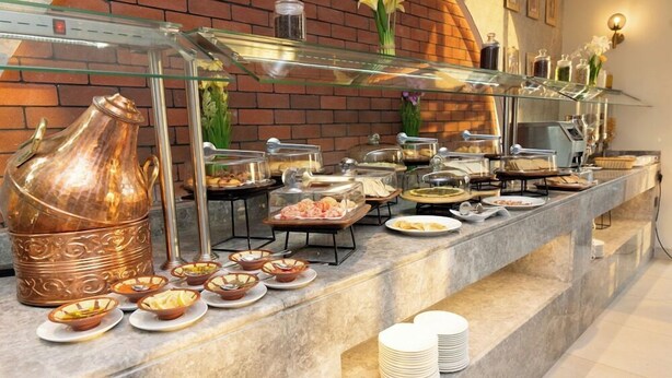 A buffet setup with various food items and a large copper pot. - Vivian Park El Raeid Hotel (Riyadh)