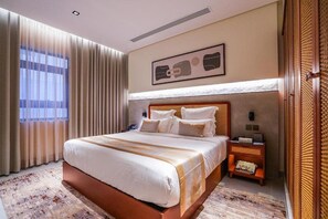 A hotel room with a large bed, a nightstand, a wall-mounted artwork, and a window with curtains. - Vivian Park El Raeid Hotel (Riyadh)