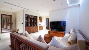 A modern living room with a sofa set, a TV, and a wooden cabinet with shelves. - Vivian Park El Raeid Hotel (Riyadh)