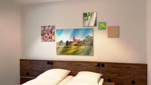 A bedroom with a wooden headboard, a bed with white linens, and three framed pictures on the wall. - Hotel Grune Elster (Fuerth)