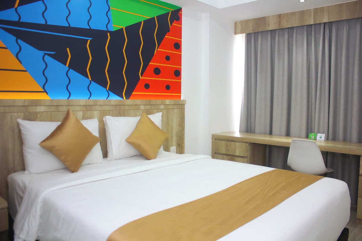 Ein Hotelzimmer mit einem großen Bett, zwei Kissen, einem Schreibtisch und einem Sessel.