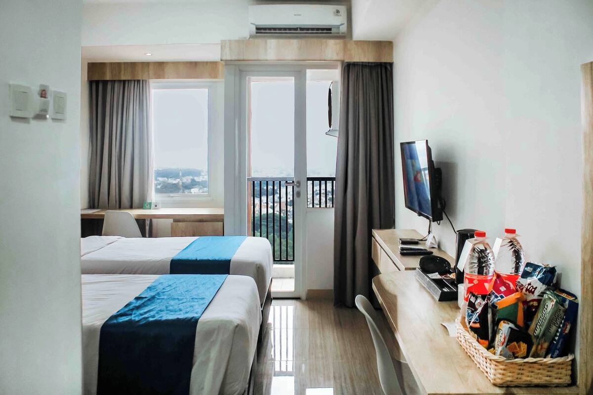 Ein Hotelzimmer mit zwei Betten, einem Schreibtisch, einem Fernseher und einem Balkon mit Blick.