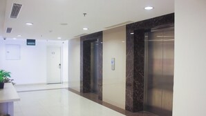 A clean, modern lobby with a marble reception desk, a reception area, and two elevators. - Urban Hotel Serpong by Zuzu (South Tangerang)