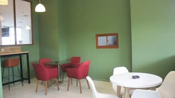 A room with green walls, a wooden table, and red and white chairs.
