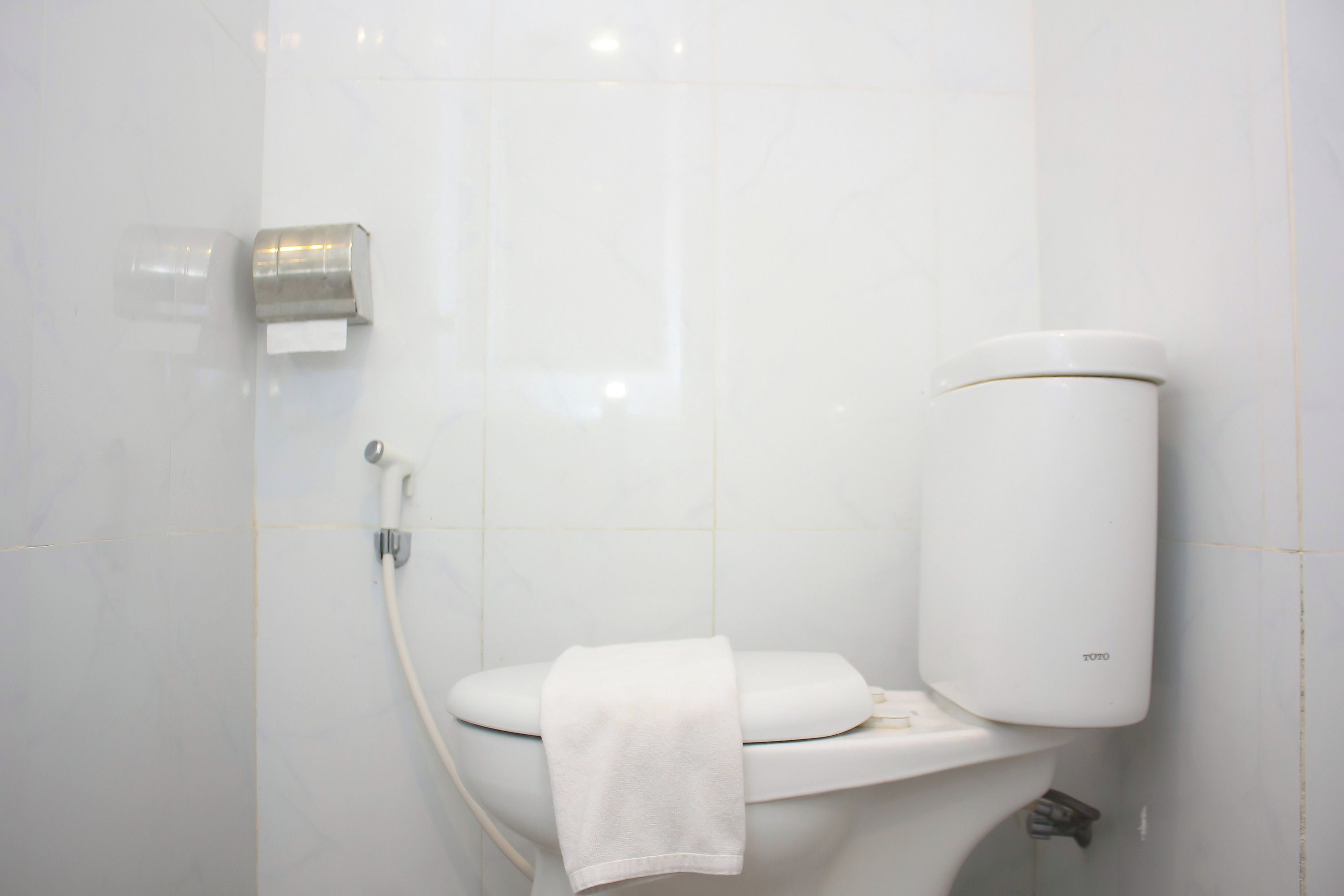 A modern bathroom with a toilet, a paper towel dispenser, and a toilet paper roll.