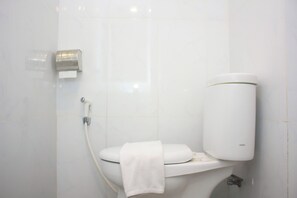 Ein modernes Badezimmer mit Toilette, Papierhandtuchspender und Toilettenpapierrolle.