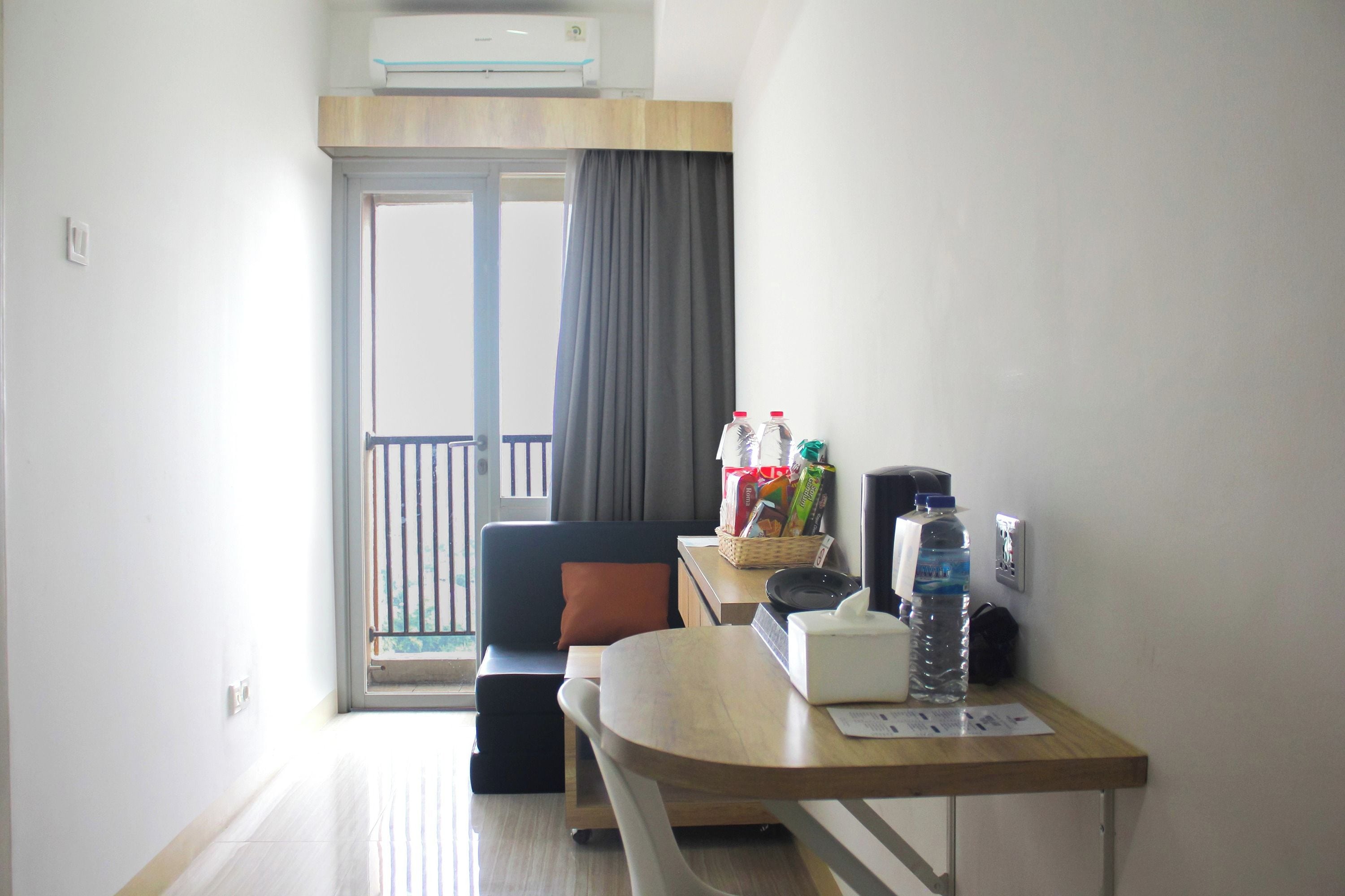 A small, bright room with a sofa, a table with a basket, a water bottle, and a tissue box.