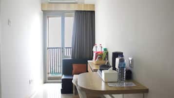 A small, bright room with a sofa, a table with a basket, a water bottle, and a tissue box.