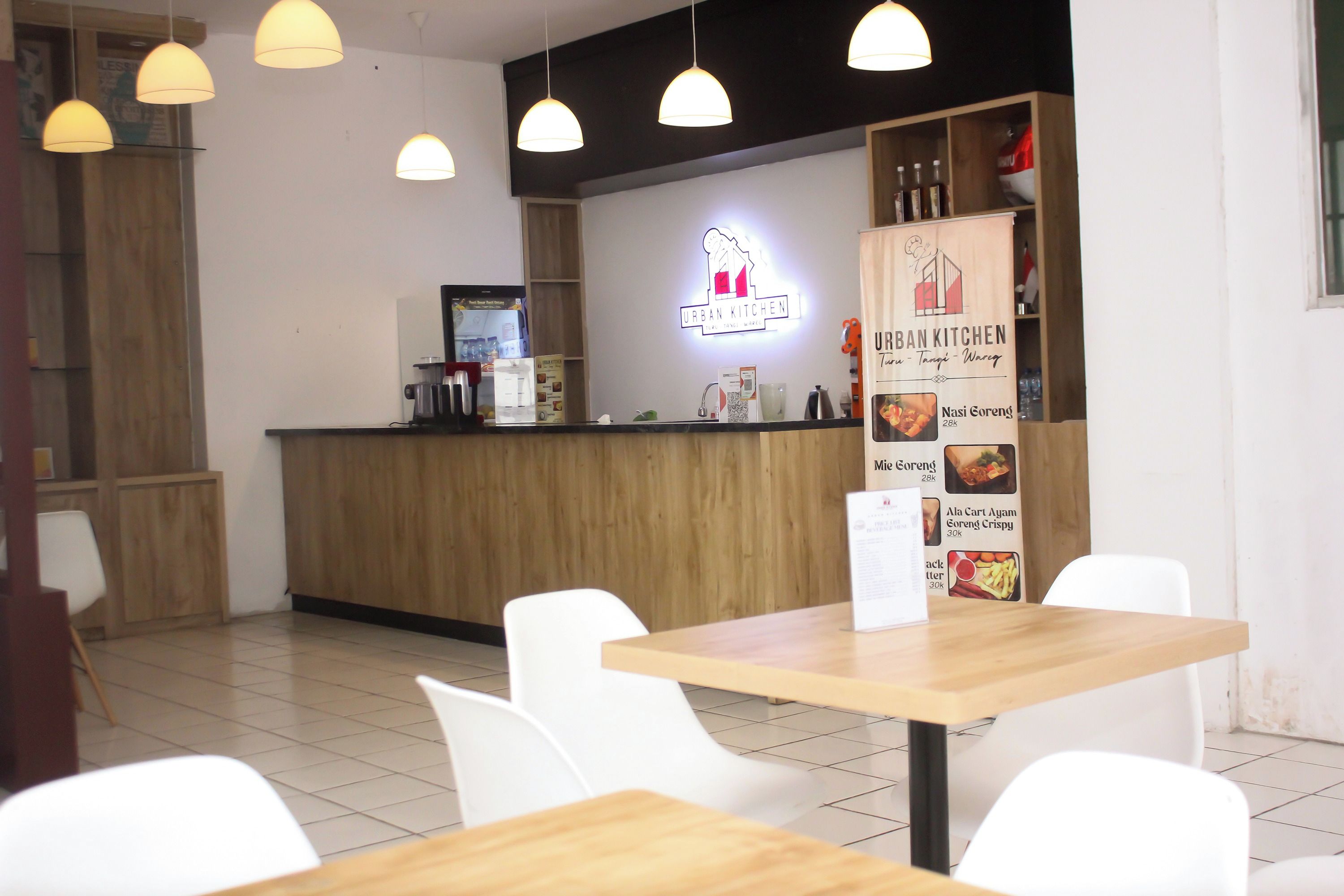 Interno di un ristorante con un bancone in legno, sedie bianche, lampade a sospensione e una lavagna con il menu.