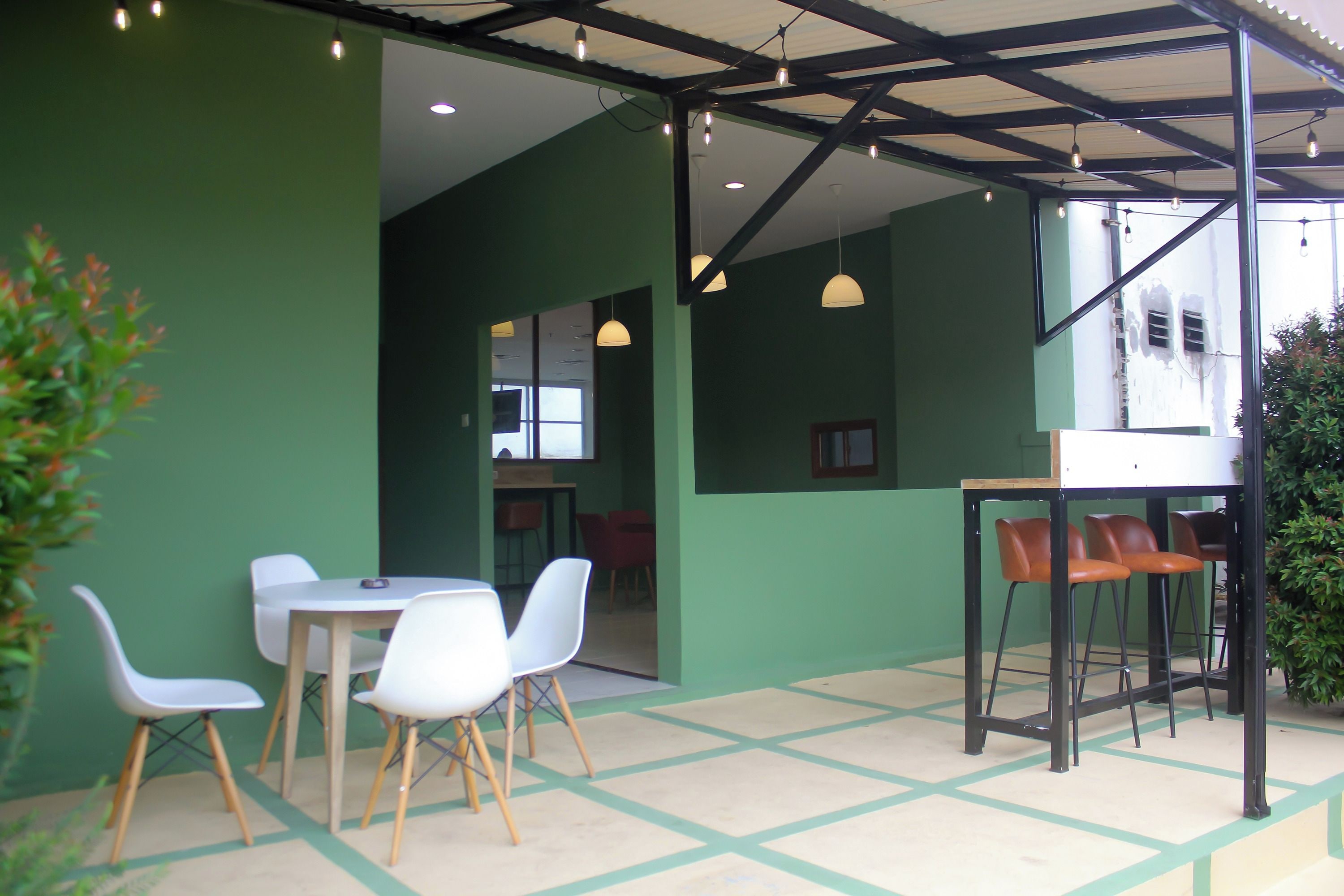 Una cafetería con interior verde, sillas blancas y una mesa de madera.