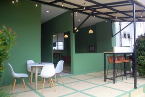 A cafe with a green interior, white chairs, and a wooden table. - Urban Hotel Serpong by Zuzu (South Tangerang)