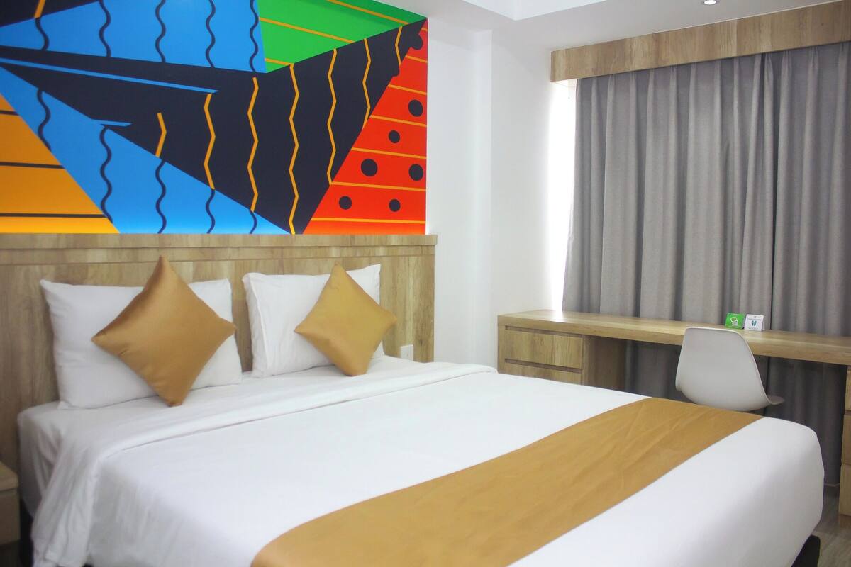 Ein Hotelzimmer mit einem großen Bett, zwei Kissen, einem Schreibtisch und einem Sessel.