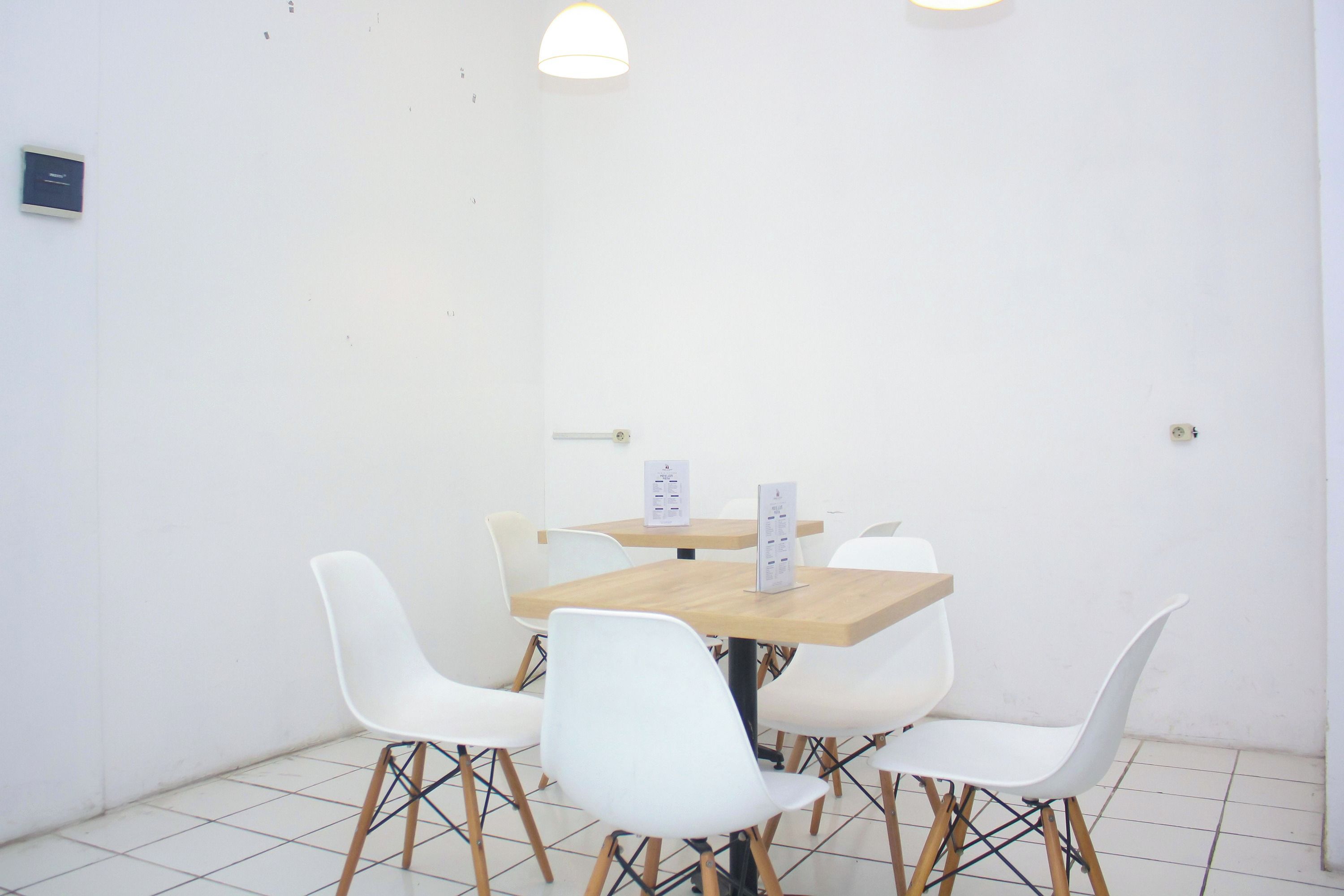 A small, clean room with a wooden table and white chairs, a whiteboard, and a clock on the wall.