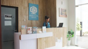 A reception desk at Urban Hotel Serpong with a wooden backdrop, a sign indicating staff-only areas, and a potted plant to the right. - Urban Hotel Serpong by Zuzu (South Tangerang)