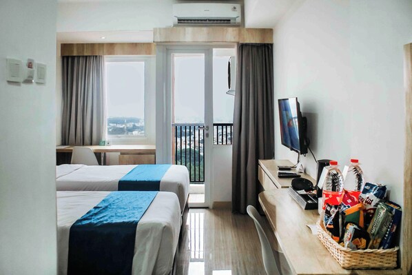 Ein Hotelzimmer mit zwei Betten, einem Schreibtisch, einem Fernseher und einem Balkon mit Blick.