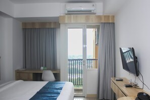 Ein Hotelzimmer mit einem Bett, einem Schreibtisch, einem Sessel, einem Fernseher und einer Klimaanlage.