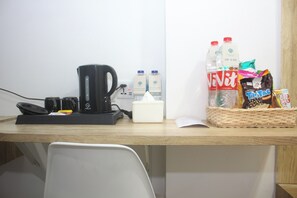Ein Schreibtisch mit Kaffeemaschine, einer Snack-Auswahl und Wasserflaschen.
