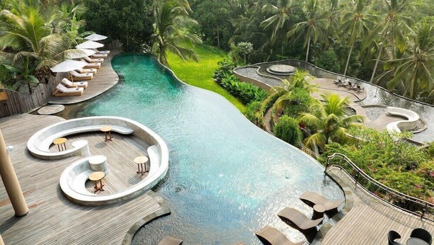 A pool area with lounge chairs and tables, surrounded by lush greenery and palm trees. - Abisena Wellness & Resort Ubud-adult Only (Tegallalang)