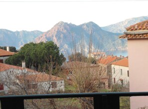 A residential area with houses, a mountain range, and a body of water in the background. - Hotel Les Calanques (Piana)