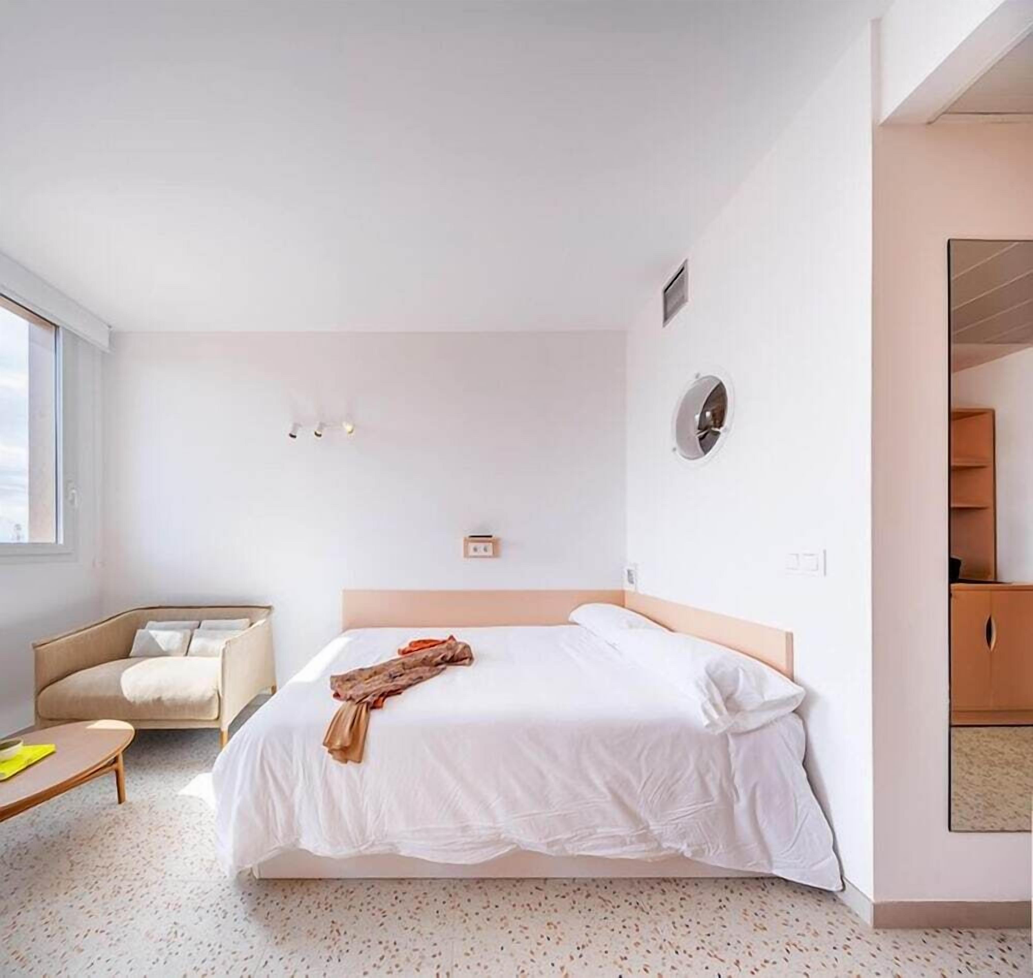 Habitación de hotel moderna con una cama grande, un área de descanso y vistas al exterior.