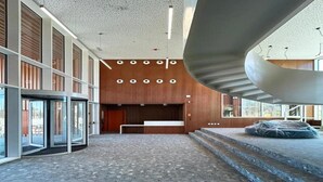 A spacious lobby with a curved staircase, a reception desk, and a large glass entrance. - Loop Homes Tower Burjassot (Burjasot)