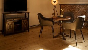 A cozy room with a TV, a round table, two chairs, and a floor lamp. - Hotel Muhlental (Wernigerode)