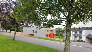 A modern building with a flat roof, a visible entrance, and a small parking area. - The Originals City, Ara Hotel, Landerneau (Landerneau)
