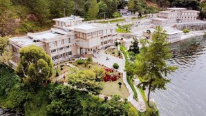 A multi-story hotel with a central courtyard, surrounded by lush greenery and a body of water. - Portola Grand Renggali Hotel (Takengon)