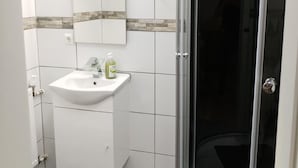 A bathroom with a white sink, a mirror, and a shower enclosure. - Hotel Radevormwald (Radevormwald)
