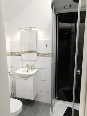 A bathroom with a white sink, a mirror, and a shower enclosure. - Hotel Radevormwald (Radevormwald)