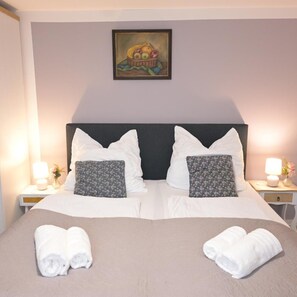 A double bed with white linens, two pillows, and two rolled towels on the bed. - Hotel Radevormwald (Radevormwald)