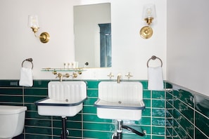 A bathroom with two sinks, a mirror, and two wall-mounted lights. - Sonder The Baker (San Diego)