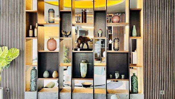 A modern interior with a central seating area, a built-in bookshelf, and a decorative wall panel.