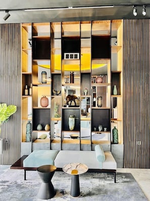 Un interior moderno con una zona de estar central, una estantería empotrada y un panel decorativo en la pared.